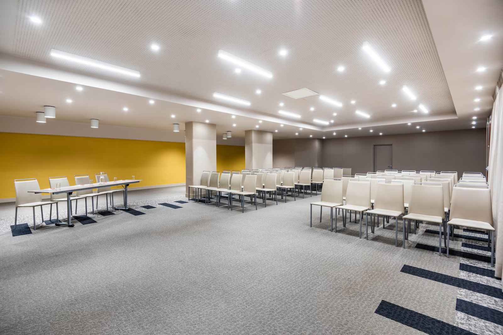 Salón amplio y entapetado dispuesto para conferencias con varias sillas alrededor.