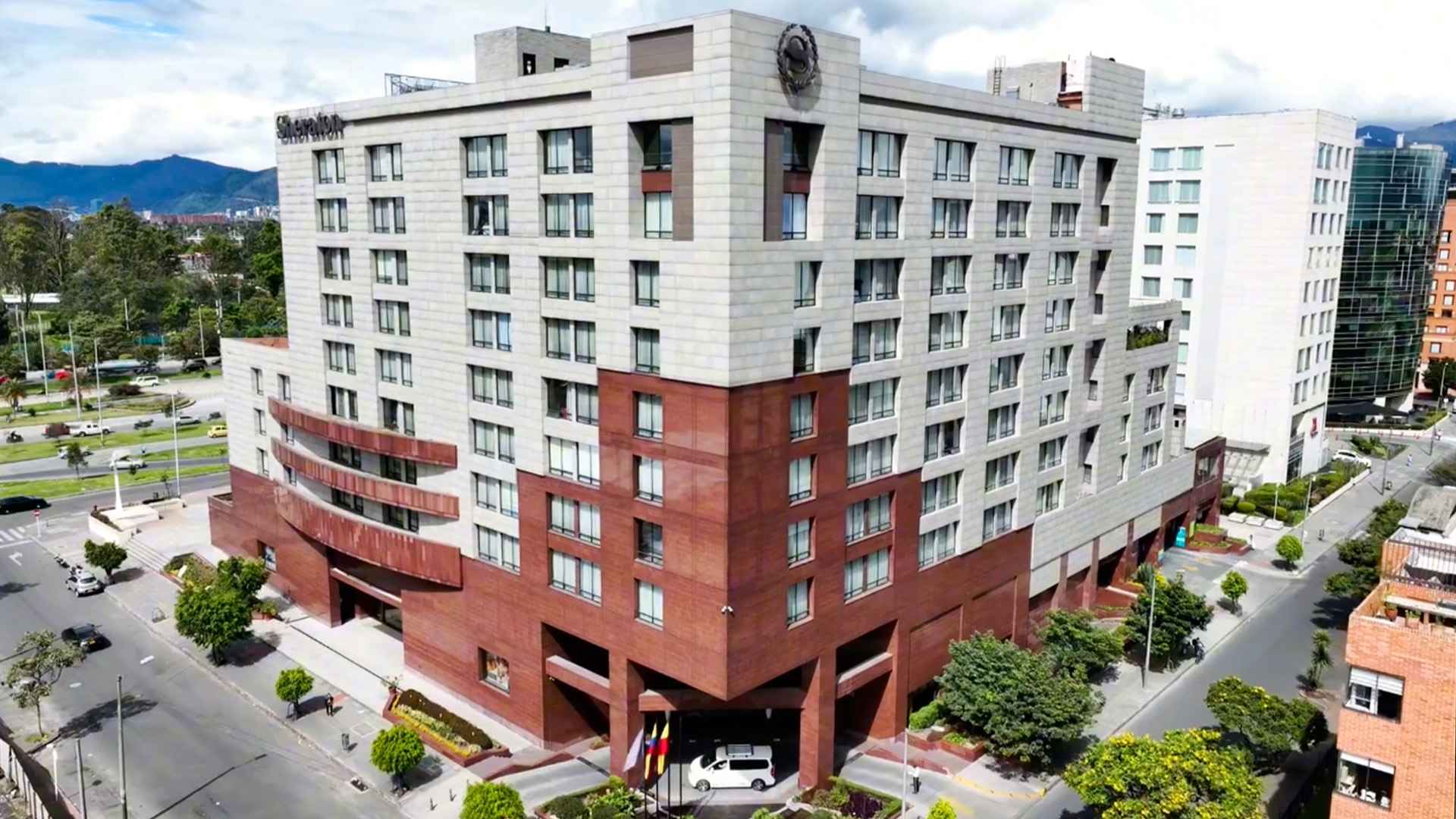 Edificio amplio y alto de casi 10 pisos, reodeado de otros edificios altos.