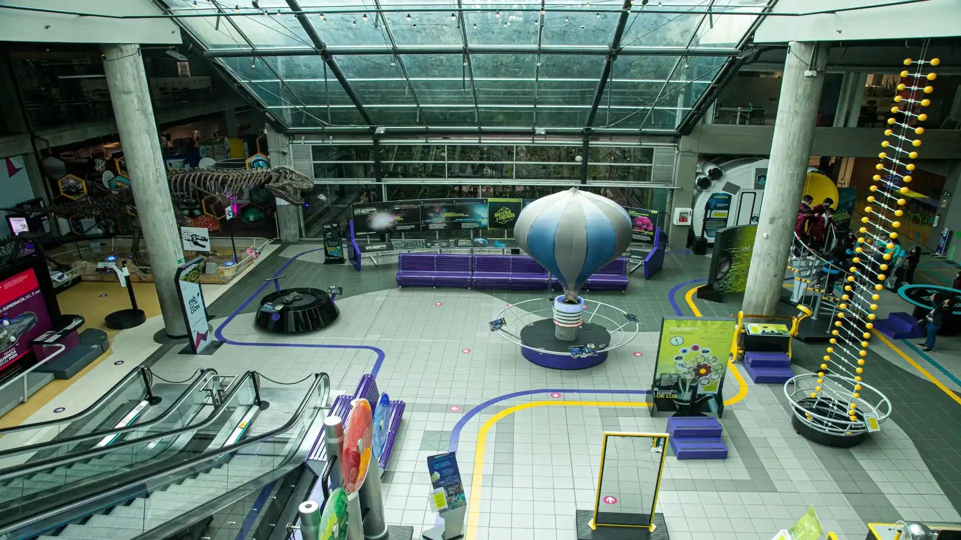 Interior space resembling a museum, where curious elements can be seen, such as a balloon, a dinosaur skeleton, and a staircase leading up to the ceiling.