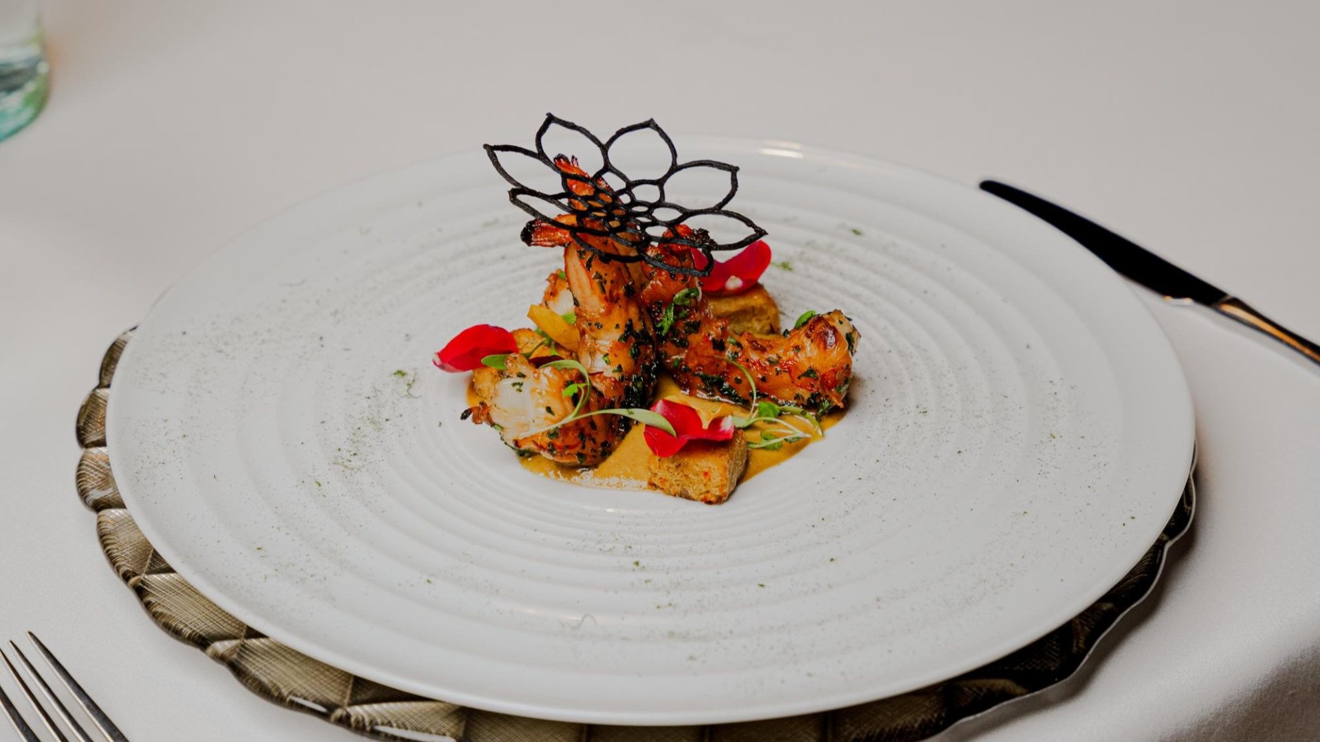  Close-up of a white plate with a gourmet dish made with prawns.