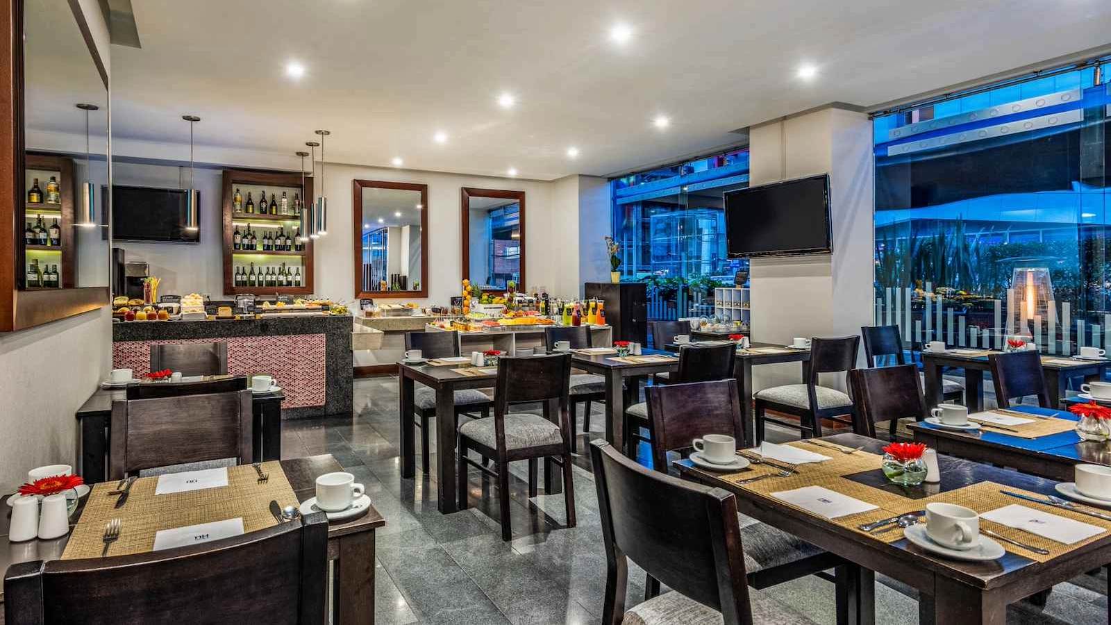 Salón de restaurante donde hay varias mesas y sillas. A un lado hay un ventanal hacia la calle.