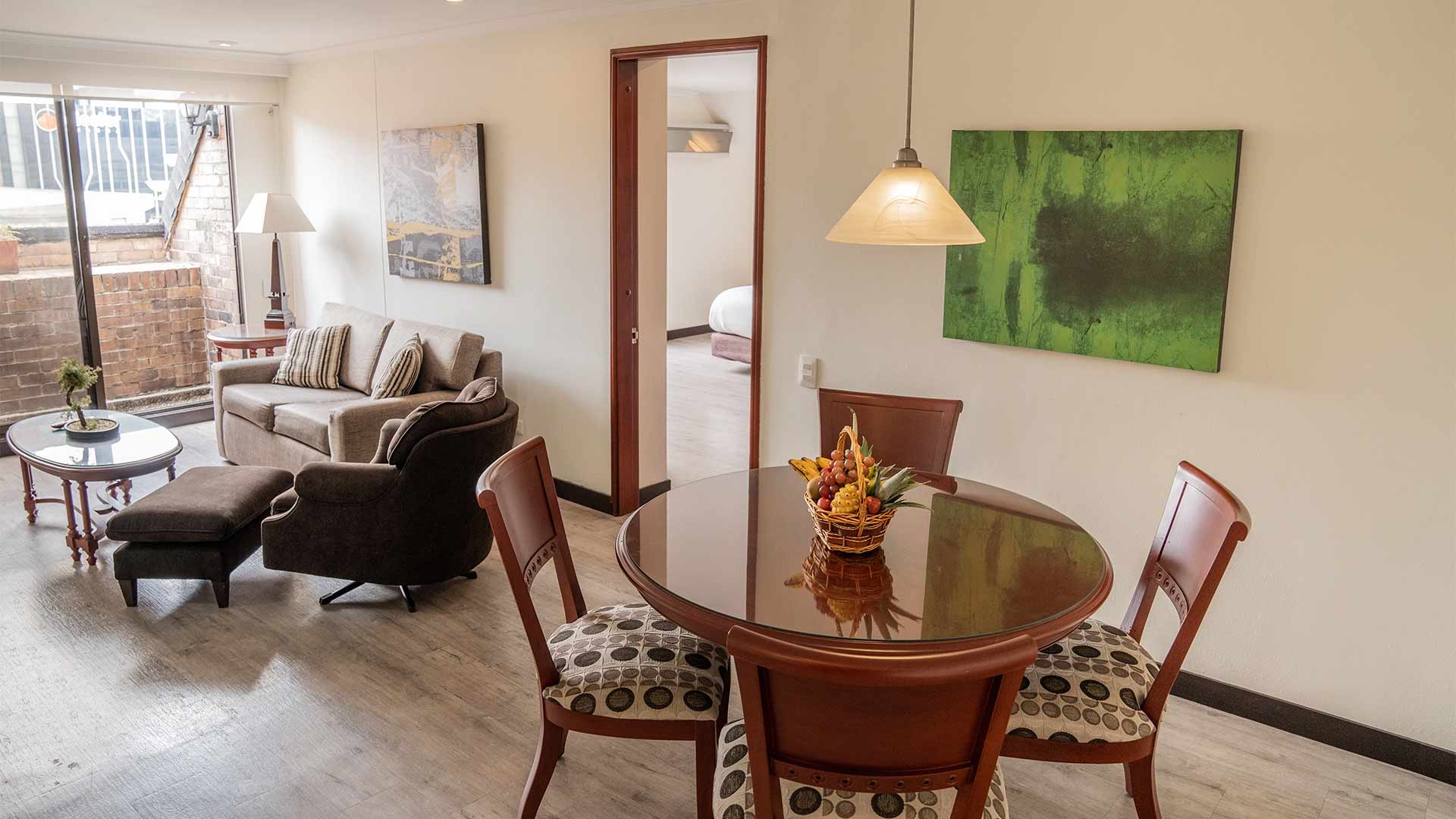  Sala con un comedor con una mesa redonda de madera, un sofa y una poltrona.