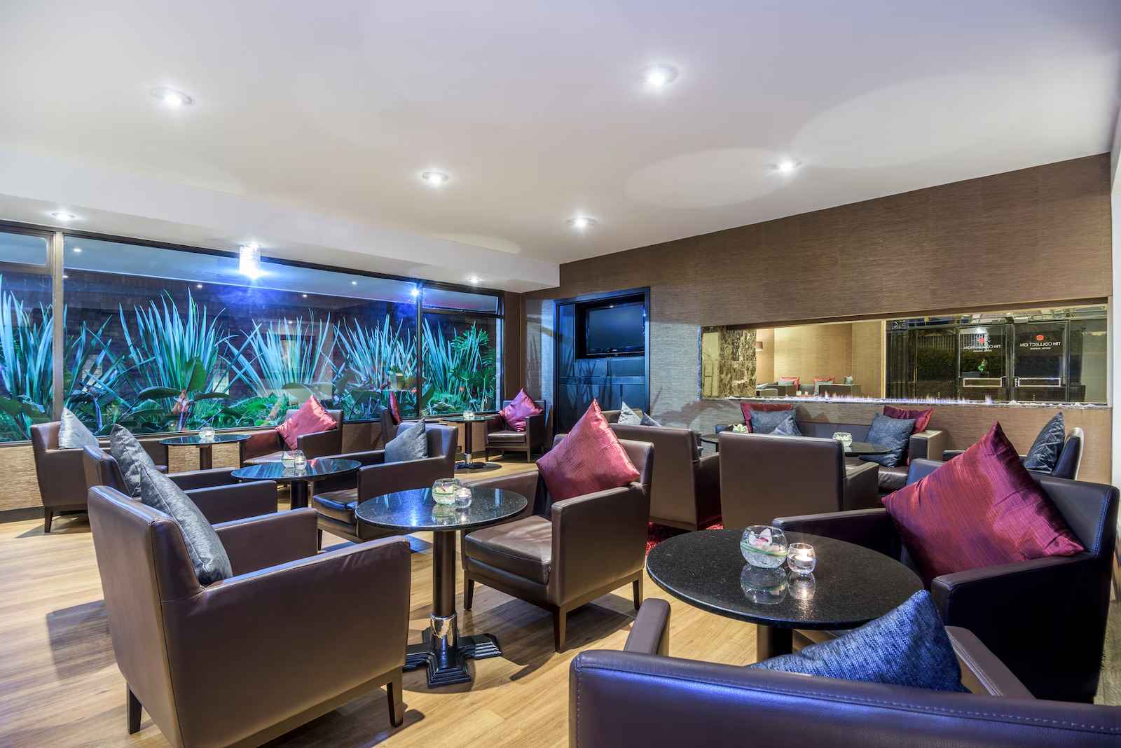 Salón de recepción en la que hay varias sillas de cuero adornadas con cojines de colores. Hay mesas redondas hechas, parece con mármol y metal.