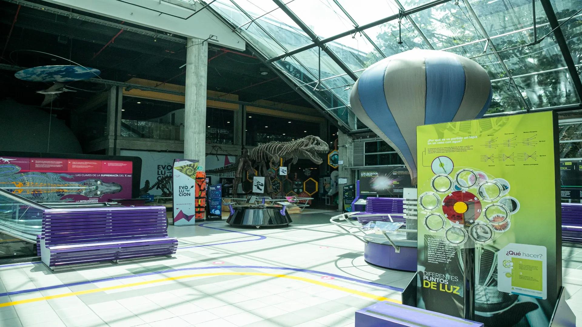 Interior space resembling a museum, where curious elements such as a balloon and a dinosaur skeleton can be seen.