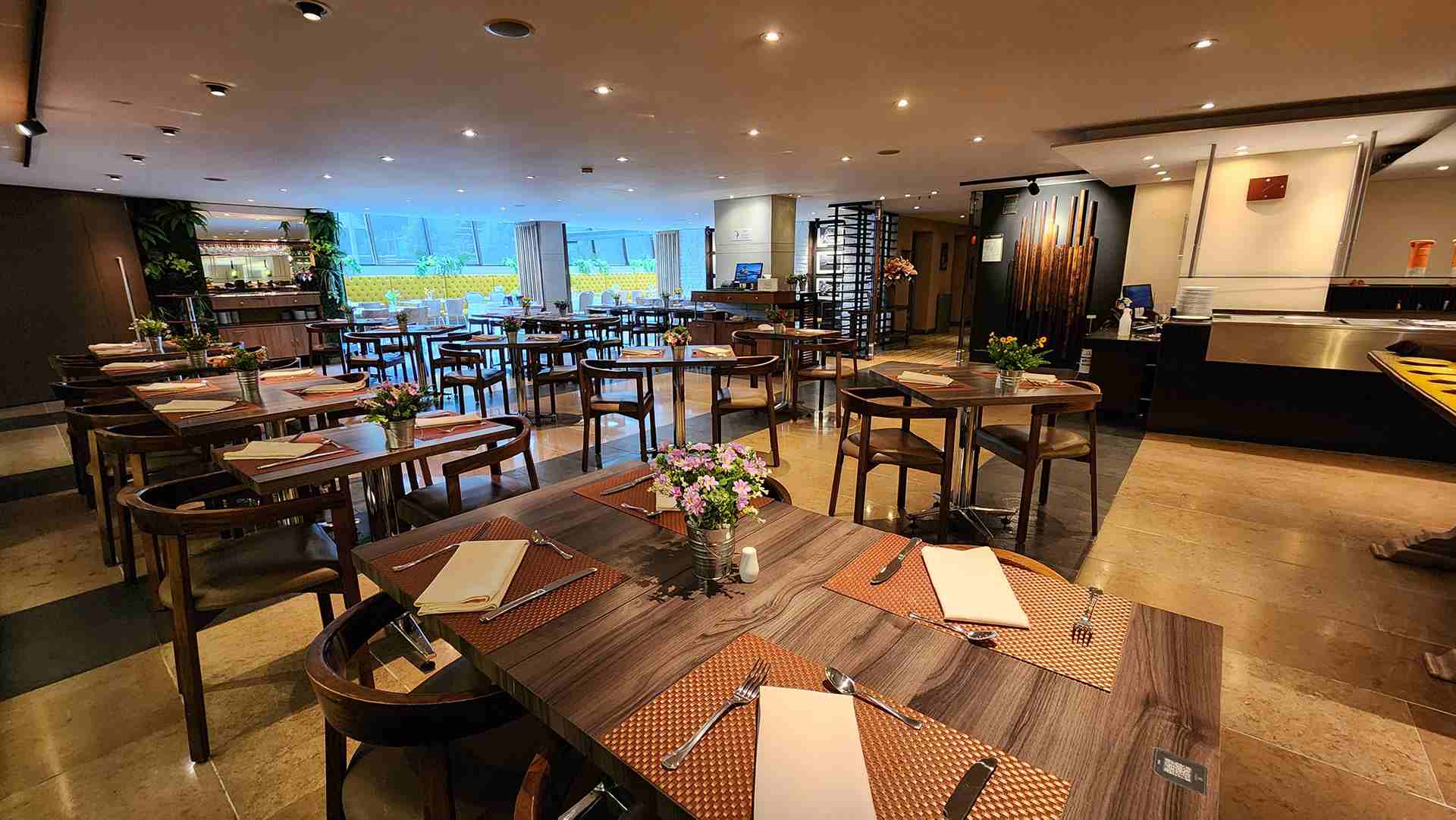 Gran salón que parece ser un restaurante con mesas y silla de madera. A un lado hay un ventanal grande hacia la calle.