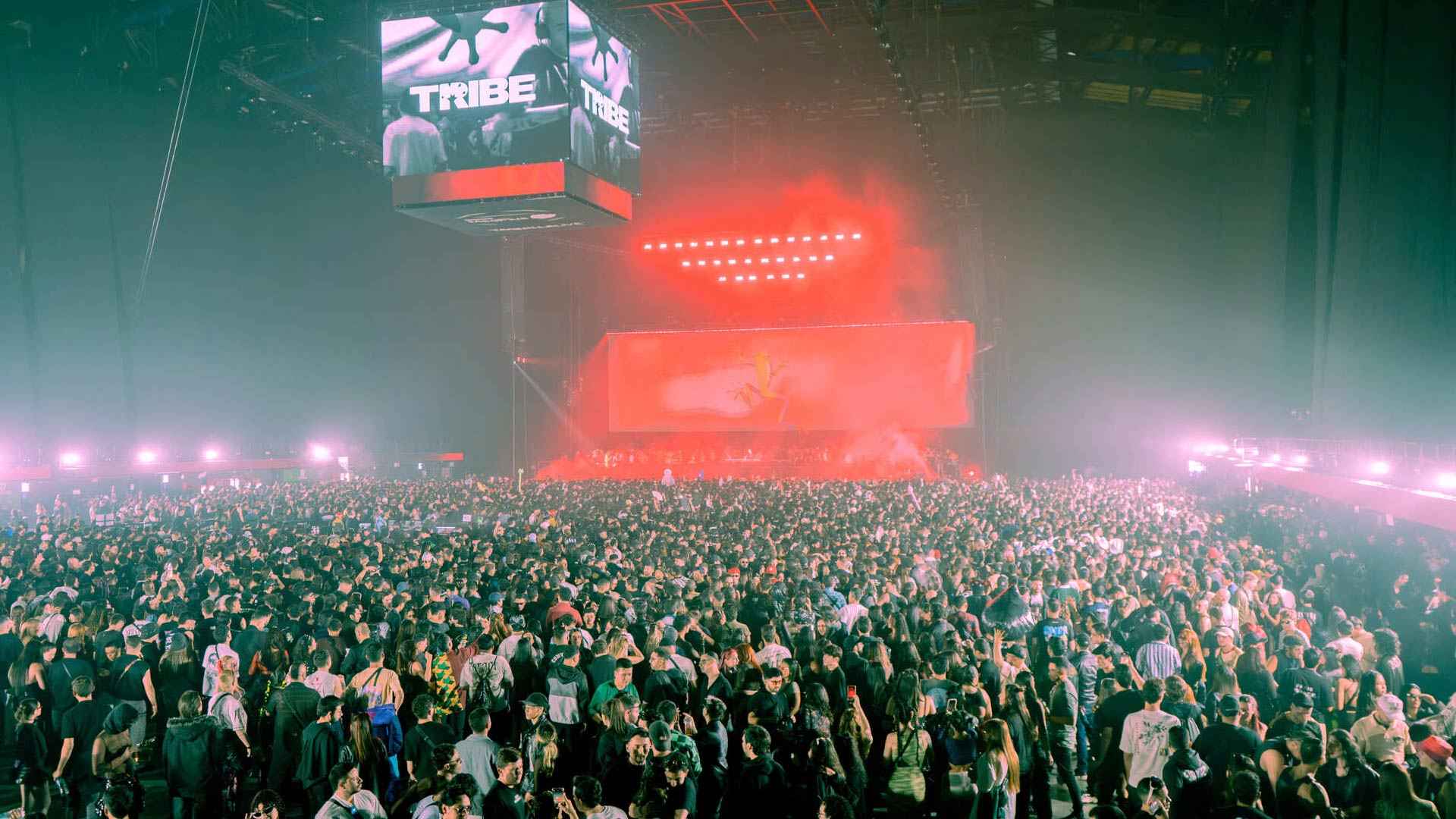  Concert stage with hundreds of people dancing in front of a colorful stage.