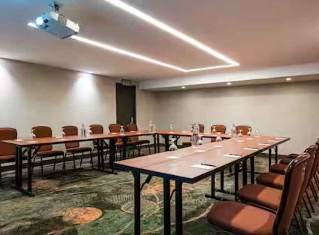  Salón con mesas organizadas en forma de U. Hay varias sillas rodeando la mesa y en ella varias copas de cristal.