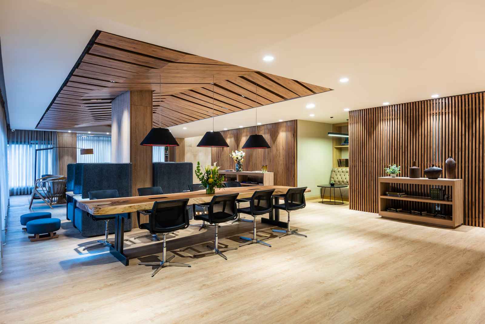 Salón pequeño que parece ser una recepción o una sala de trabajo en la que sobresale una mesa alargada con varias sillas al rededor. Techo y paredes tienen decoraciones de madera.