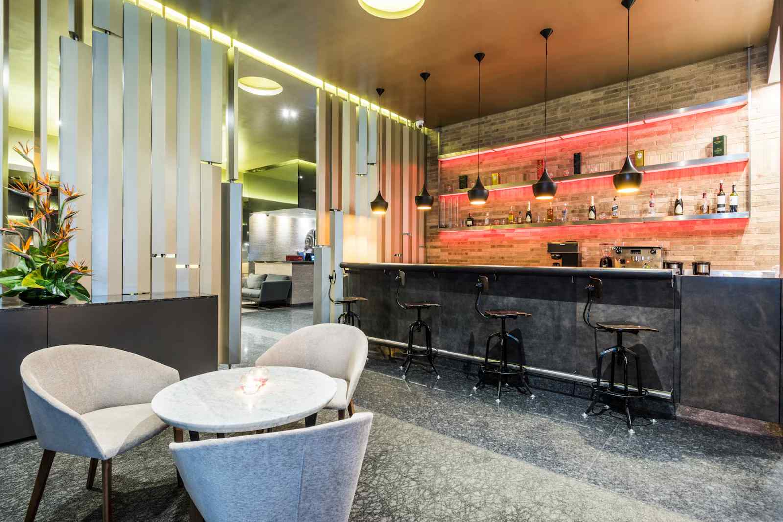  Salón pequeño con un mesón y una estantería con varias botellas de licor.