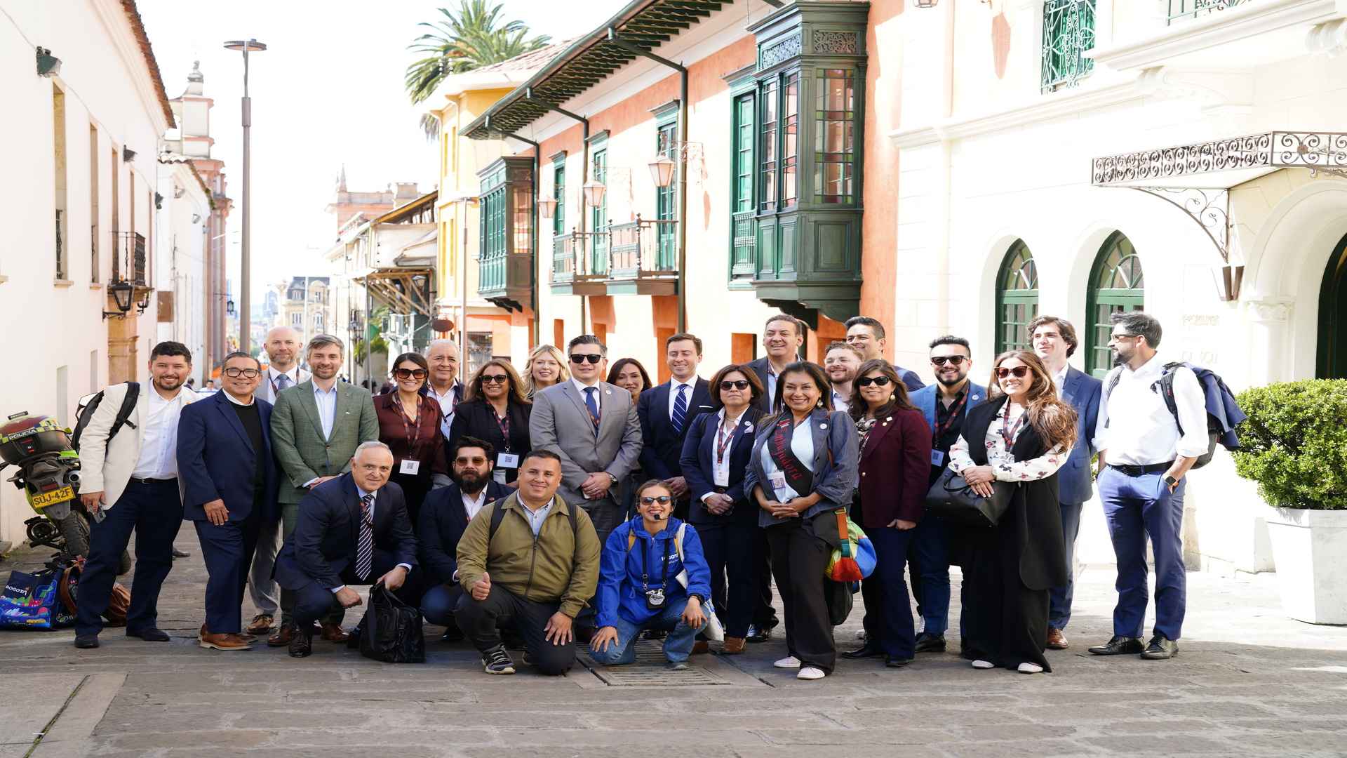 Descripción: Un grupo grande de personas, algunos en trajes de negocios, posando en una calle histórica adoquinada.