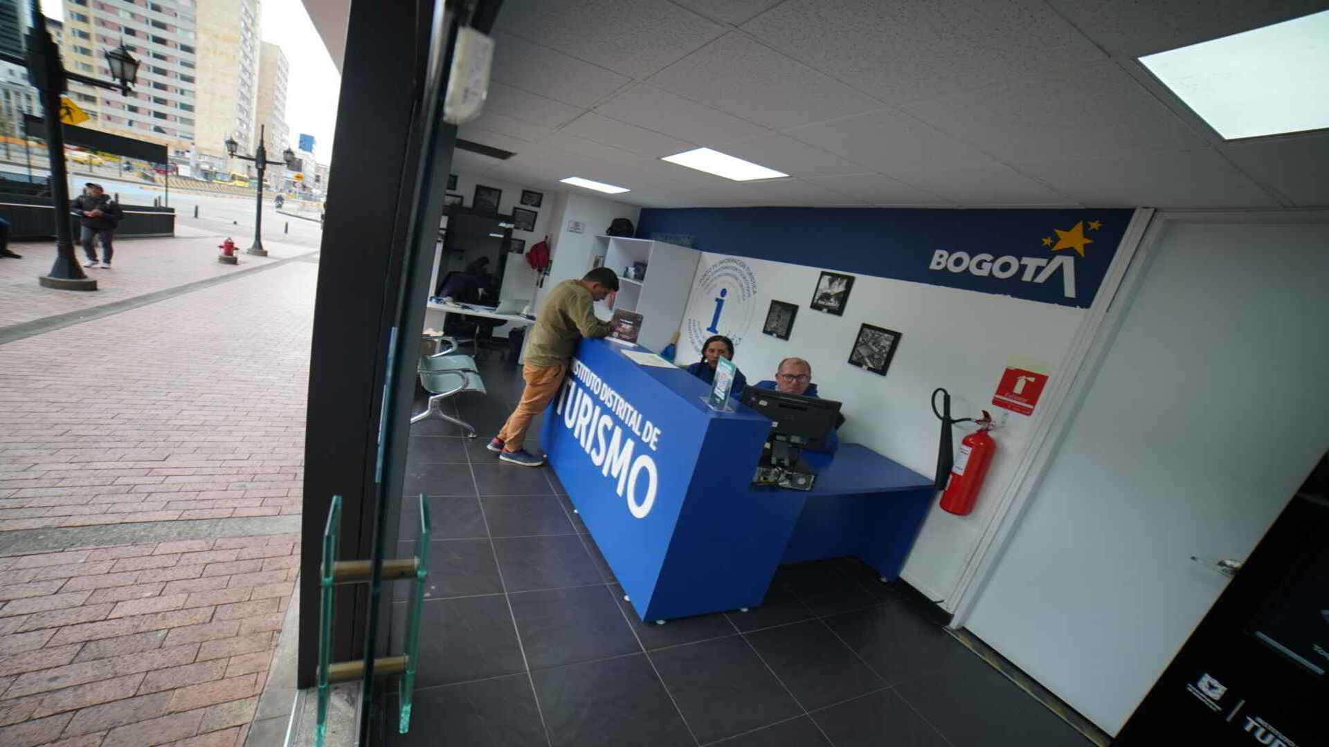  Interior de un centro de información turística de Bogotá, con personal atendiendo a un visitante. 