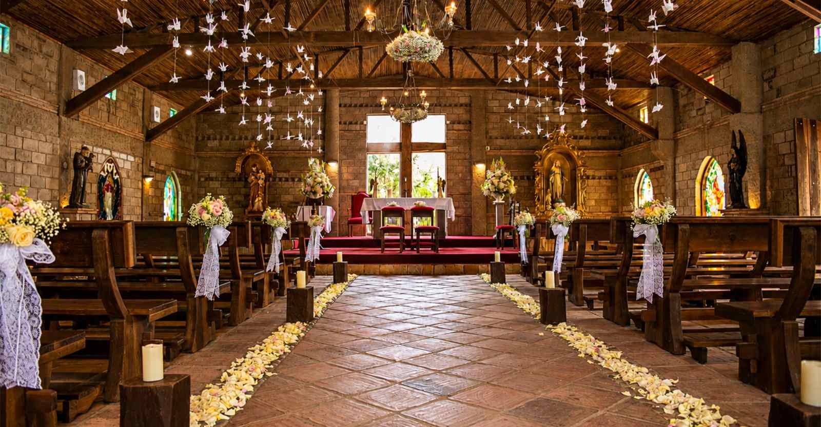  Una hermosa capilla de estilo rústico se viste de flores, velas y delicados detalles para una ceremonia especial. La madera, la piedra y la decoración floral crean un ambiente íntimo, romántico y lleno de calidez, ideal para celebrar momentos inolvidables.