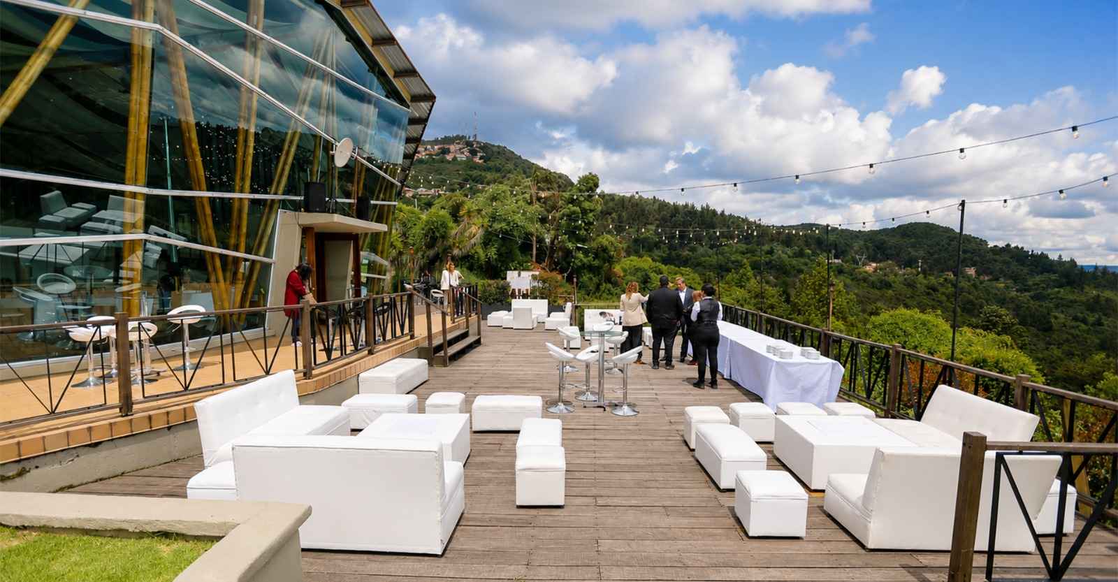  Un espacio al aire libre rodeado de naturaleza, con amplias zonas verdes, terraza y una moderna estructura en madera y vidrio. El entorno ofrece una combinación de arquitectura, paisaje y comodidad, ideal para realizar eventos y disfrutar de una experiencia al aire libre con una vista privilegiada.