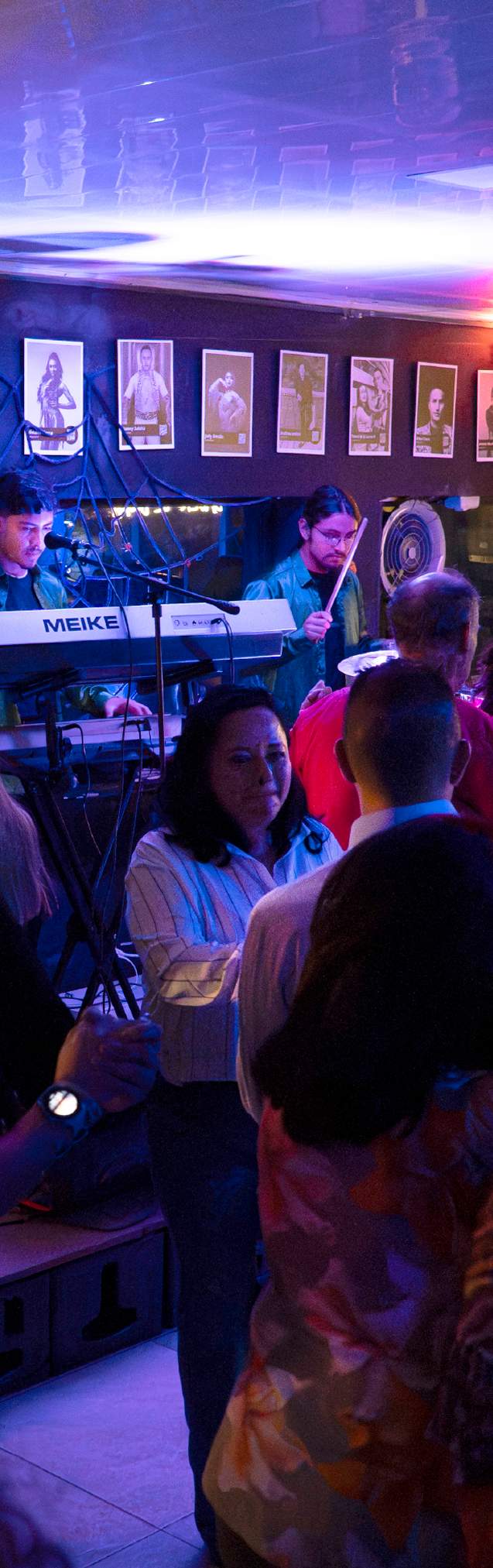 Público disfruta de una noche de música en vivo en un bar de Bogotá, iluminado por luces de colores.