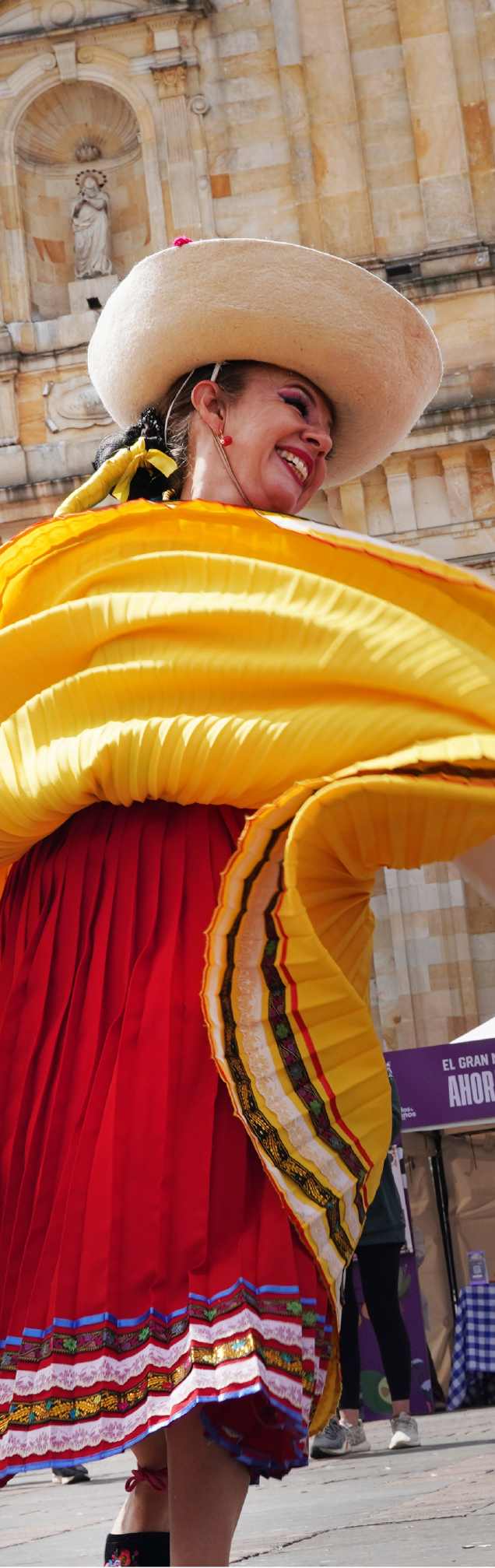 Mujer participa en una celebración tradicional en el centro de Bogotá, luciendo un colorido traje típico.