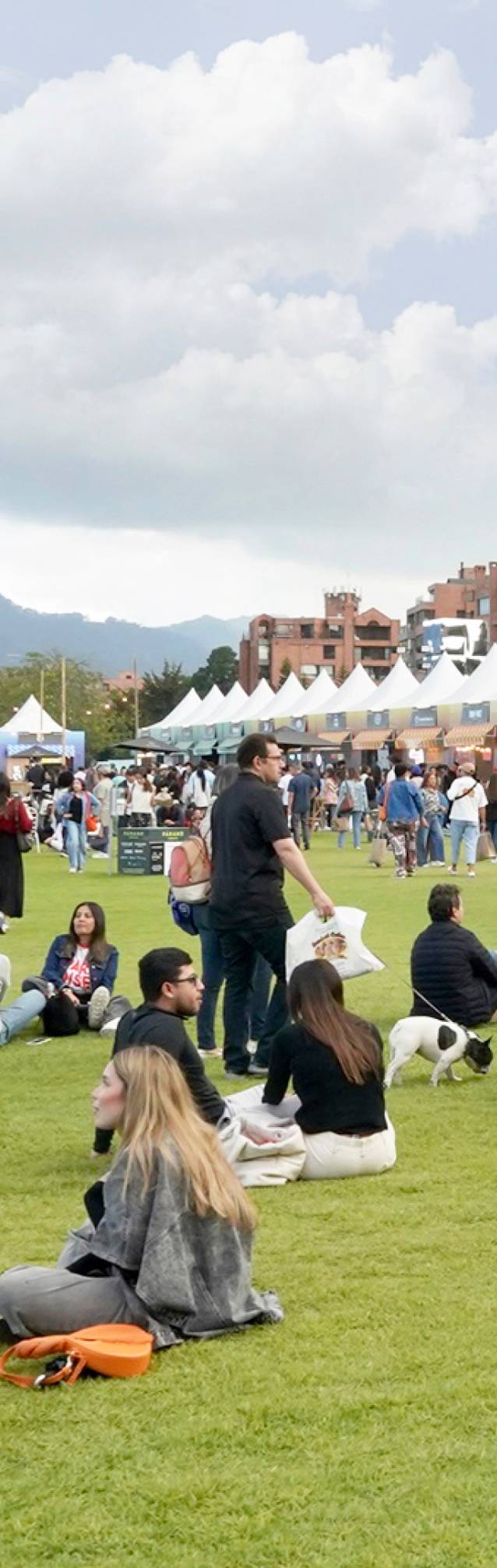 Visitantes recorren una feria al aire libre en Bogotá, entre puestos comerciales y actividades para el público.