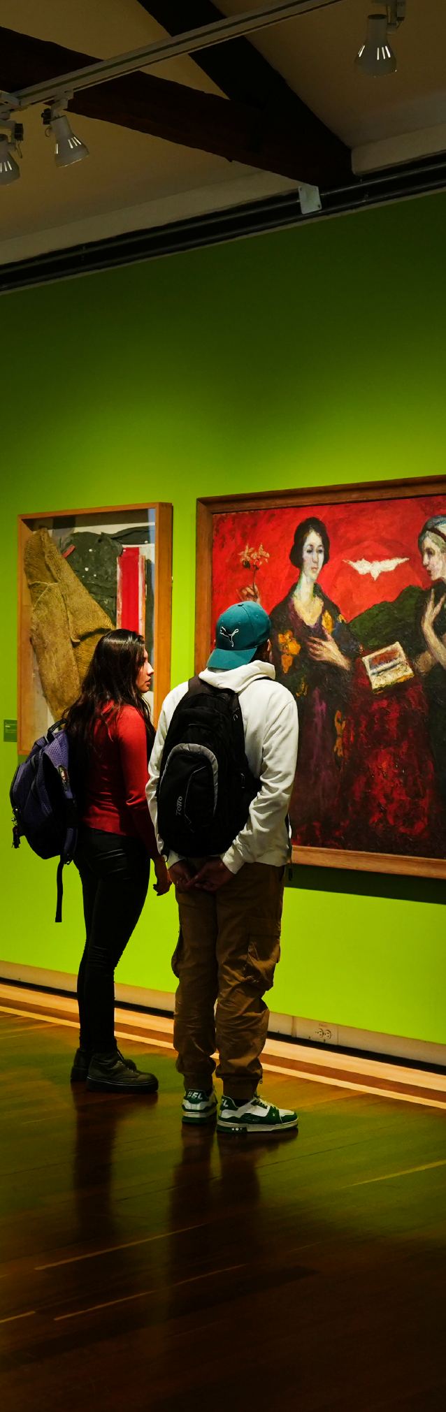 Visitantes observan obras de arte en una sala de museo, en un recorrido por el patrimonio cultural de Bogotá.