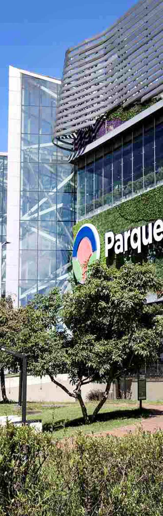 Fachada de un moderno centro comercial de Bogotá, rodeado de jardines y zonas verdes.