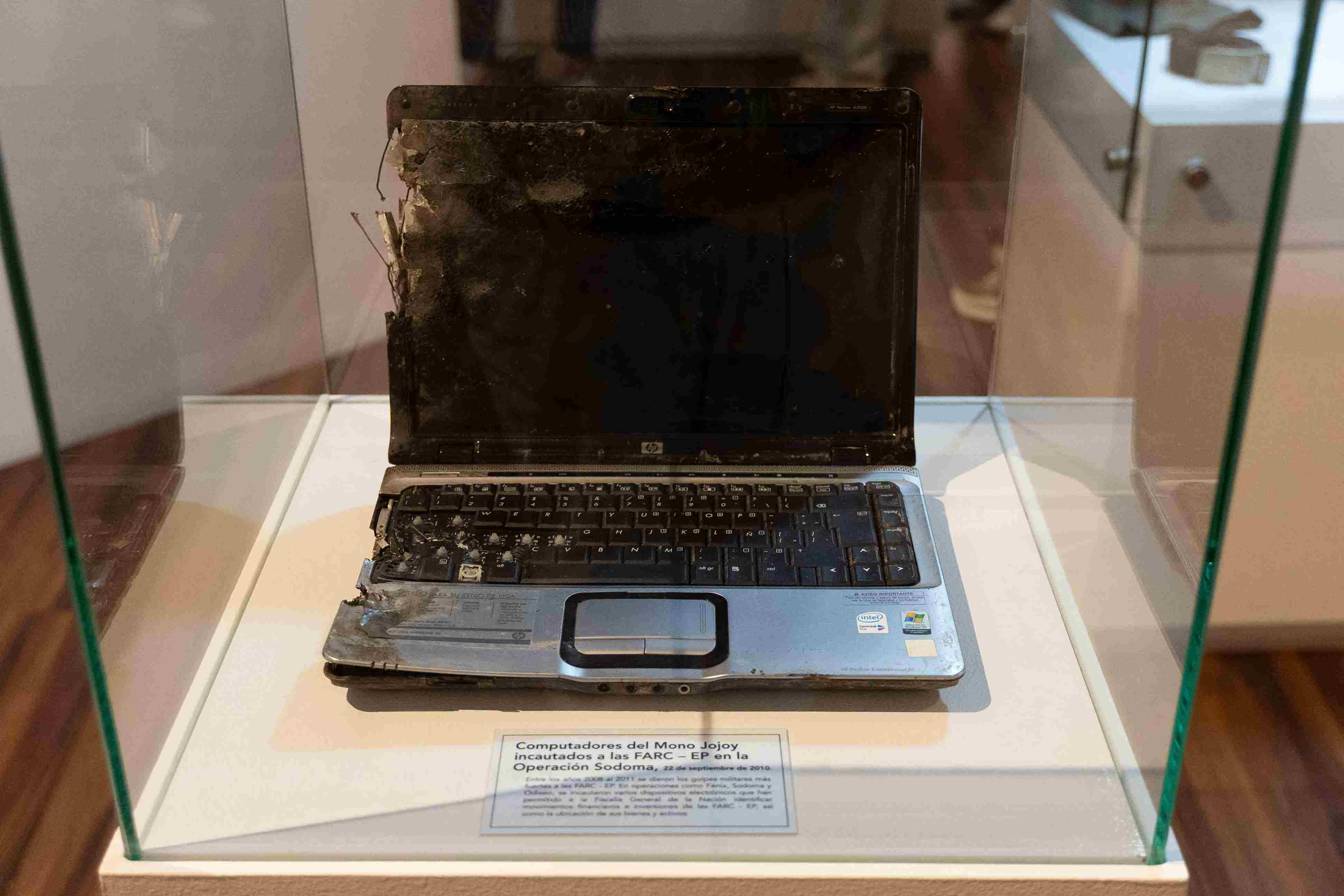 Computador portátil deteriorado, exhibido en una vitrina del Museo de la Fiscalía General de la Nación como evidencia incautada durante la Operación Sodoma contra las FARC-EP.
