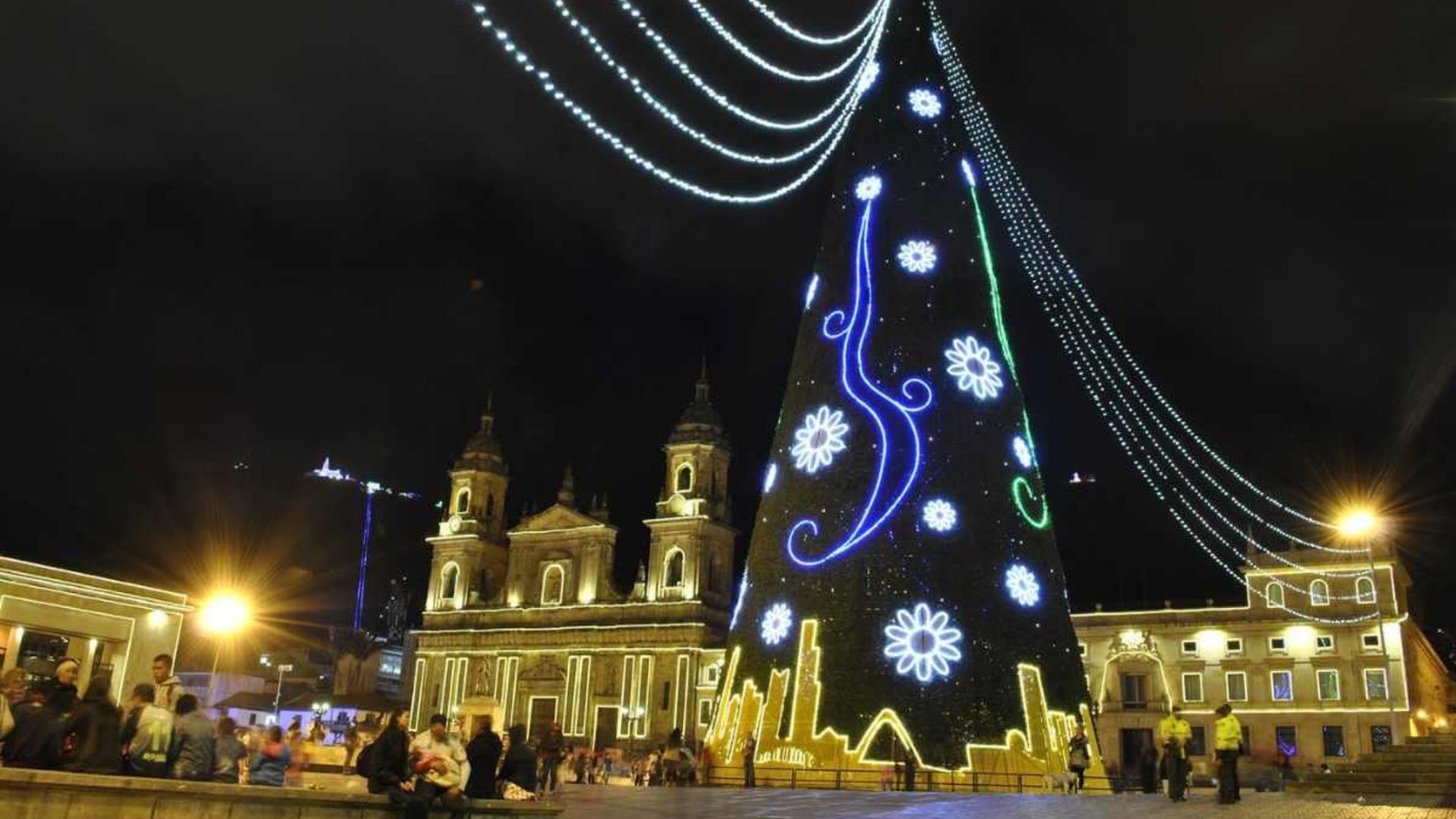 Gran árbol de Navidad encendido frente a la Catedral Primada iluminada en la Plaza de Bolívar.