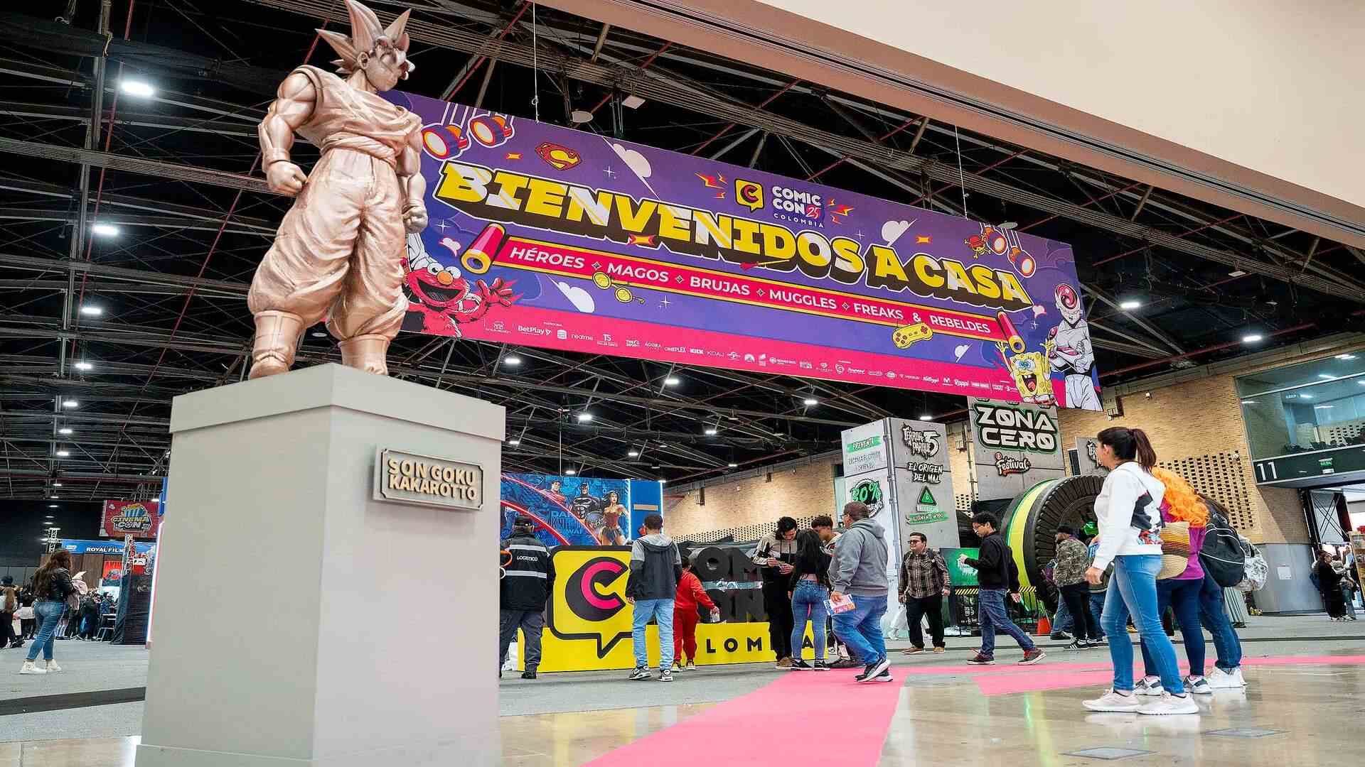 Estatua dorada de Goku en primer plano frente a un gran letrero morado que dice "Bienvenidos a casa" en la Comic-Con.