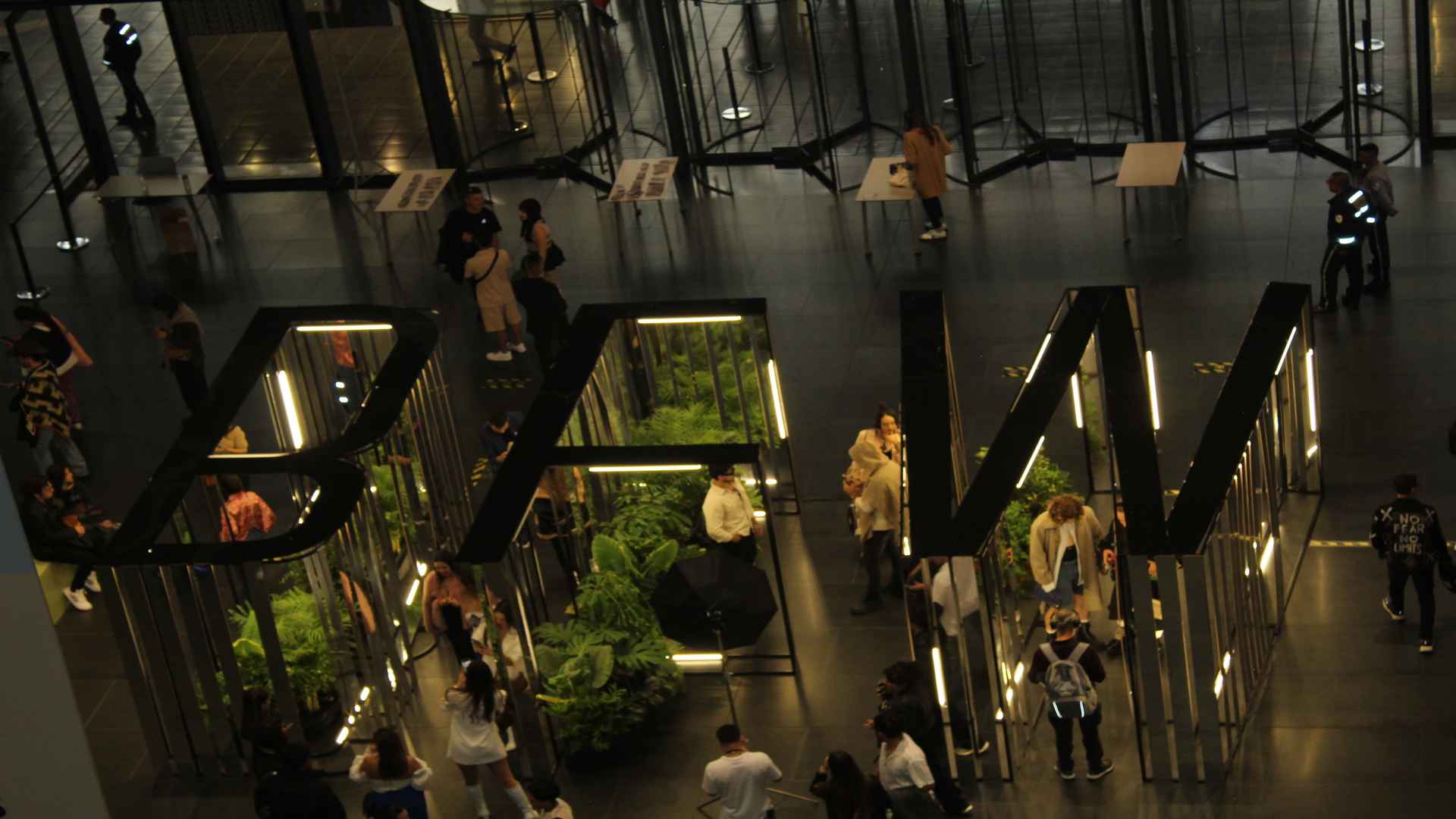 Entrada a Ágora BFW. Gran cartel BFW, plantas, gente expectante. Letrero BFW Bogotá Fashion Week en Ágora, Centro de Convenciones.
