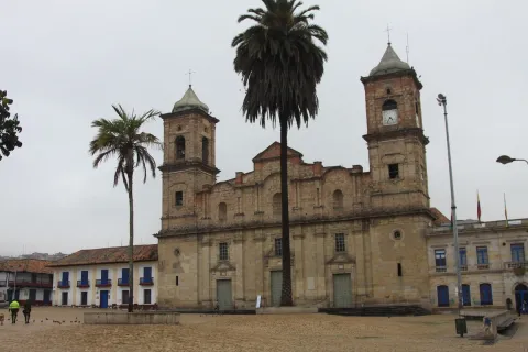  Catedral Santísima Trinidad y San Antonio de Padua, fachada frente de día cielo gris y un par de palmas a los costados. Dos personas caminan al frente.