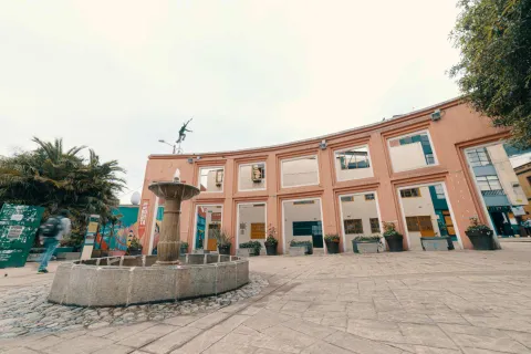 Chorro de Quevedo Square, wide view of the central water fountain and the large wall with a sculpture of a clown on a unicycle above it.