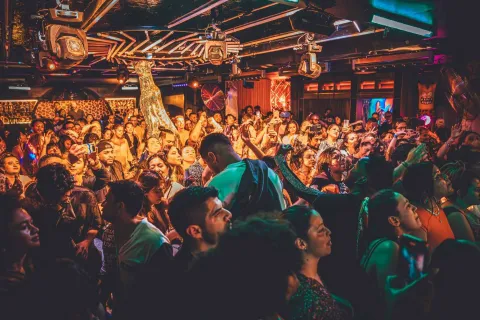 Disco Jaguar salón atestado con decenas de personas que bailan y ríen rodeando una figura de jaguar dorado.