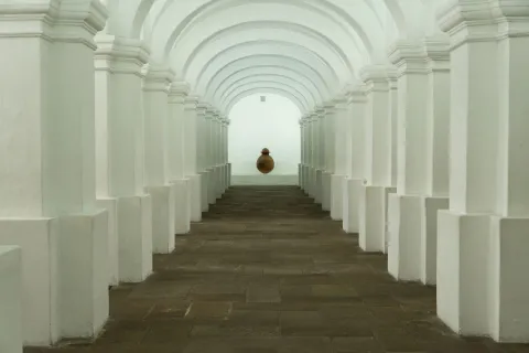National Museum of Colombia, interior corridor with white walls and columns forming oval arches. At the end, a round clay vessel is visible.