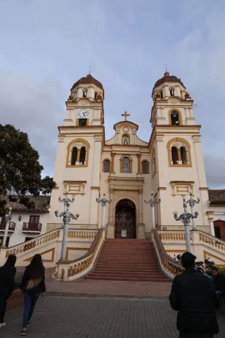 Basílica Menor de San Jacinto en primer plano de fachada vista en contrapicado con dos mujeres y un hombre que camina hacia su puerta. El cielo está gris.