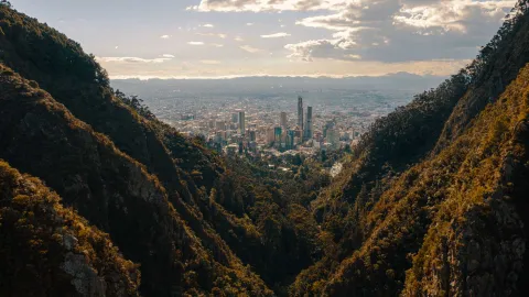 Eastern Hills with the city seen between two tree-covered mountains. The sky is gray and cloudy.