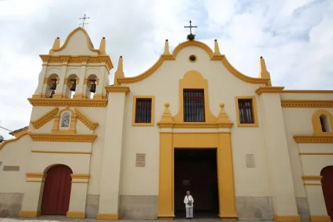 Sanctuary of Our Lady of Health - Bojacá, front view of the façade with an adult woman standing at the closed main door.