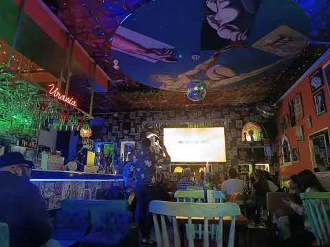 Inside Brokeback Mountain decorated interior with colorful photos and painted walls.  People talking and watching a screen