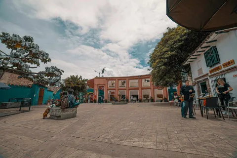 Chorro de Quevedo Square in a wide shot of the square with people gathered. The sky is blue with scattered clouds.