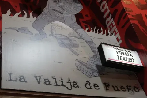 Librería La Valija de Fuego su afiche en primer plano con el nombre de la librería con un aviso con luz en el que se lee Música, Poesía y Teatro.