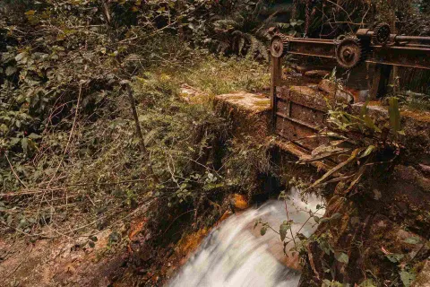 Sendero San Francisco - Vicachá profusa caída de agua sobre puente metálico rodeado de vegetación.