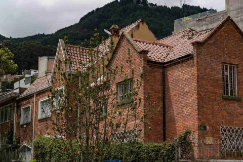 Chapinero plano general de fachadas casas estilo inglés en ladrillo, techos con teja de barro, algunas flores al frente y al fondo de los techos los cerros orientales.