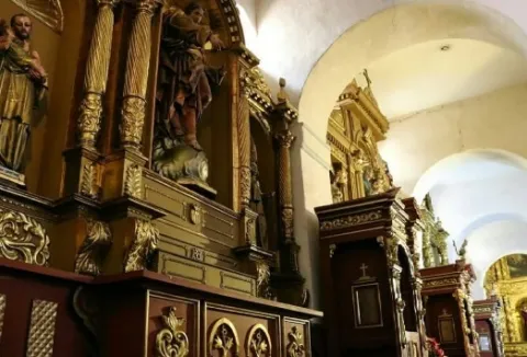 Iglesia de la Candelaria colonial en el interior con retablos en una pared decorada con esculturas religiosas y sus columnas en forma de arcos.