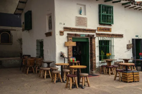 Chorro de Quevedo Square, colonial two-story white facade house adapted as a restaurant with tables and chairs set outside.