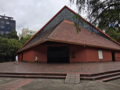  Parroquia Inmaculada Concepción de frente fachada de forma triangular con personas caminando cerca.