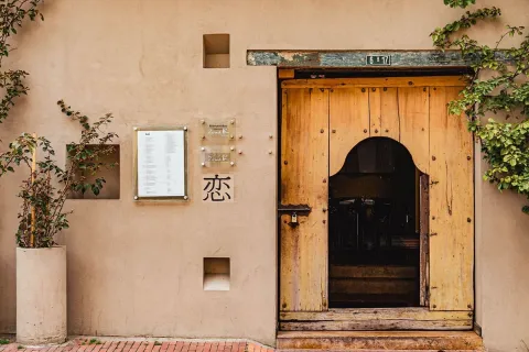 Fachada de un restaurante de estilo rústico en Usaquén, con una puerta de madera tallada que evoca la tradición y la cultura de la zona. Al lado, un menú da la bienvenida a los visitantes.