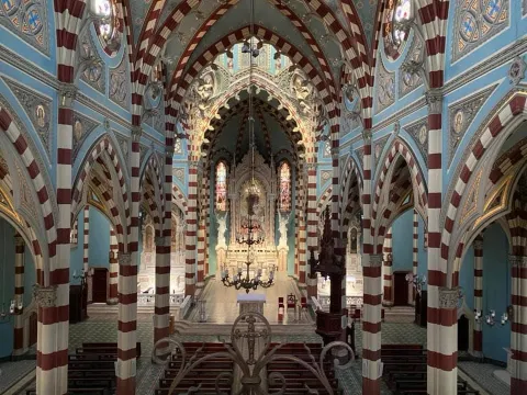  Santuario Nuestra Señora del Carmen al interior vista desde el segundo piso destacan las columnas y los arcos ovalados. Hay dos ventanas circulares a los lados por donde ingresa un leve haz de luz y una gigante lámpara cuelga del techo.
