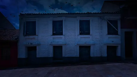 Casa antigua de fachada blanca y negra en La Candelaria con tono azul de anochecer.