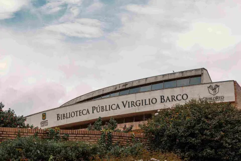 Brick and stone facade prominently displaying the name of the Virgilio Barco Library. The sky is gray.
