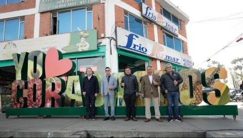 Grupo de hombres adultos parados al frente de un aviso gigante que dice "Yo amo Corabastos". Todos están con una copa en la mano.