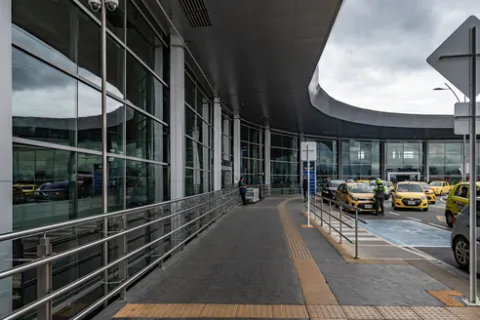 Exterior of a building with many windows. Several taxis are parked in front.