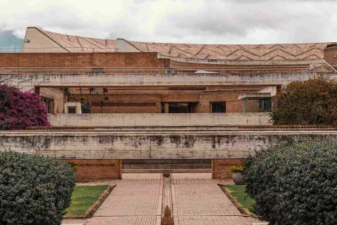 Structure with brick and concrete walls and floor. Several flowers and plants grow along the sides.