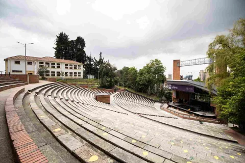 Oval-shaped brick gallery or grandstand. In the background, an old, two-story, white building is visible.