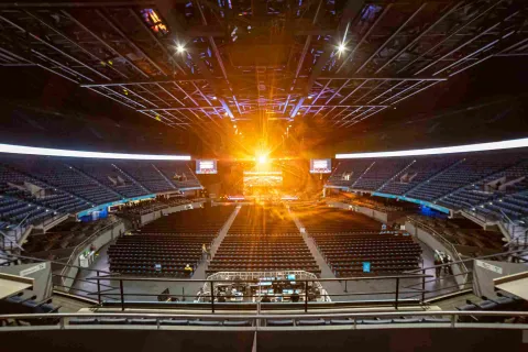  Escenario interno en el que se ven tribunas desocupadas y un haz de luz brillante dorada que viene desde la tarima.